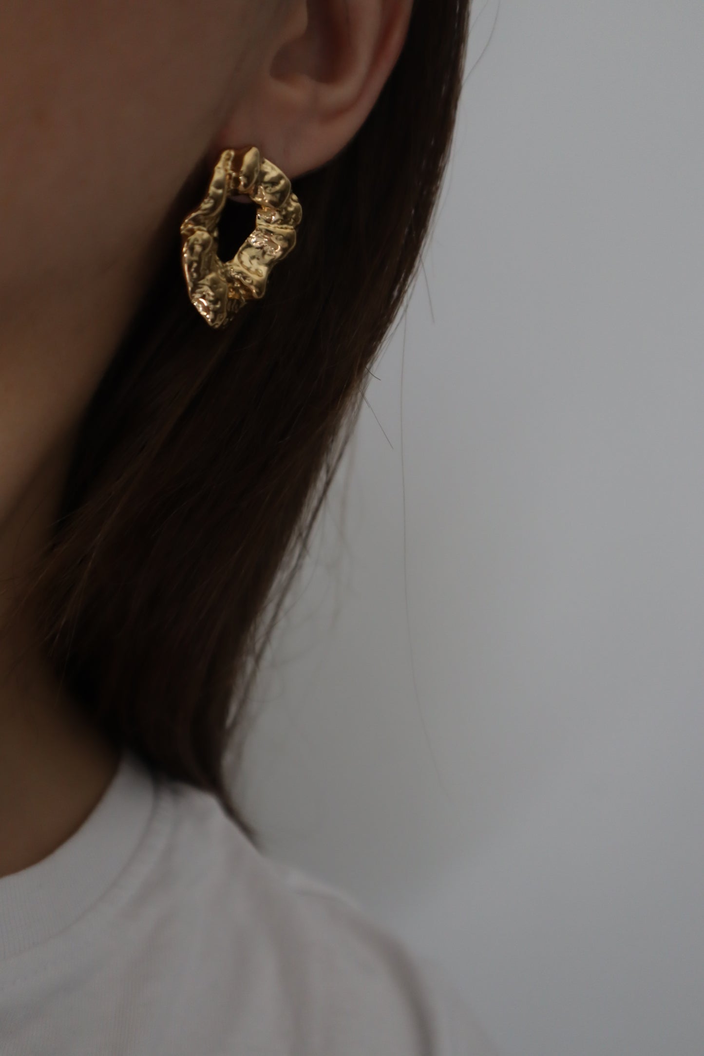 Brincos Amoreira dourados com design rústico irregular em aço inoxidável.