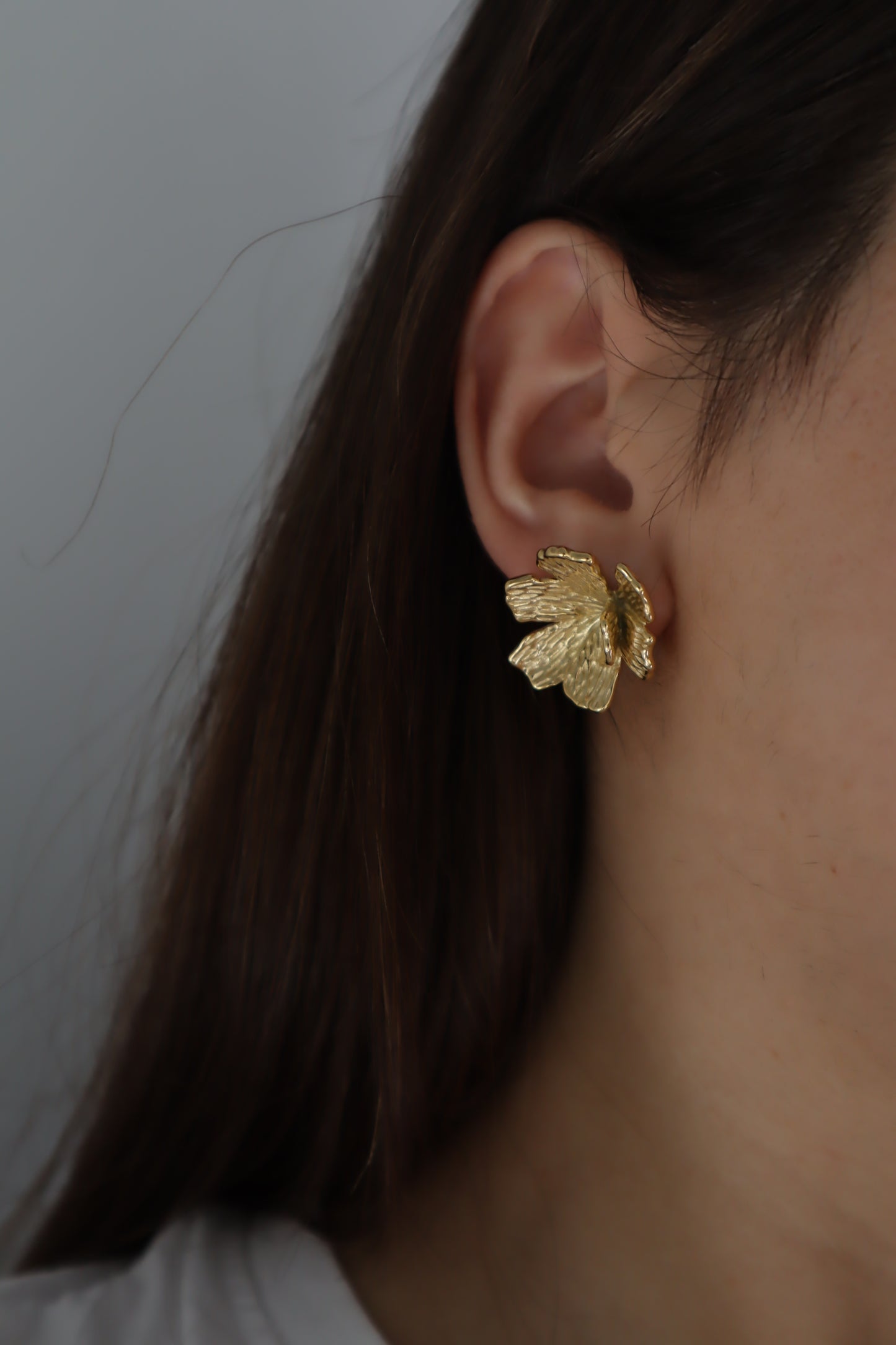 Brincos Jade em aço inoxidável dourado, design floral com parte inferior removível, para dois estilos distintos.