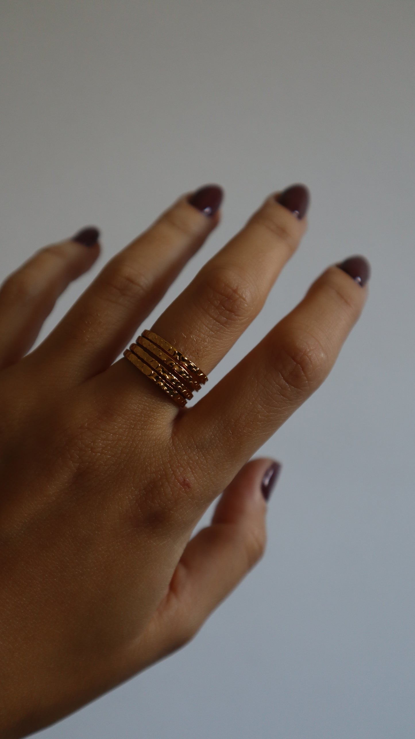 anel Amie dourado com múltiplos aros e textura rugosa em aço inoxidável