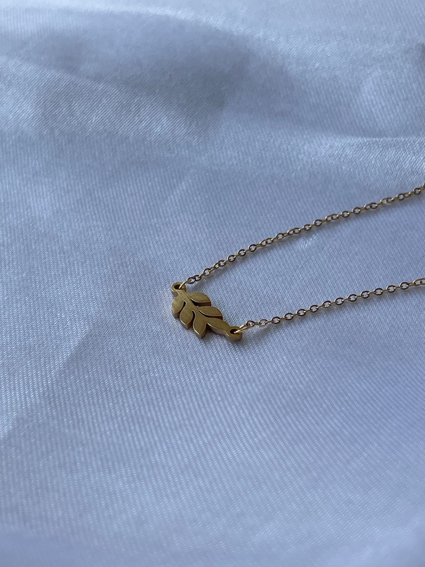 Colar Baunilha dourado com pendente em formato de folha, feito em aço inoxidável.