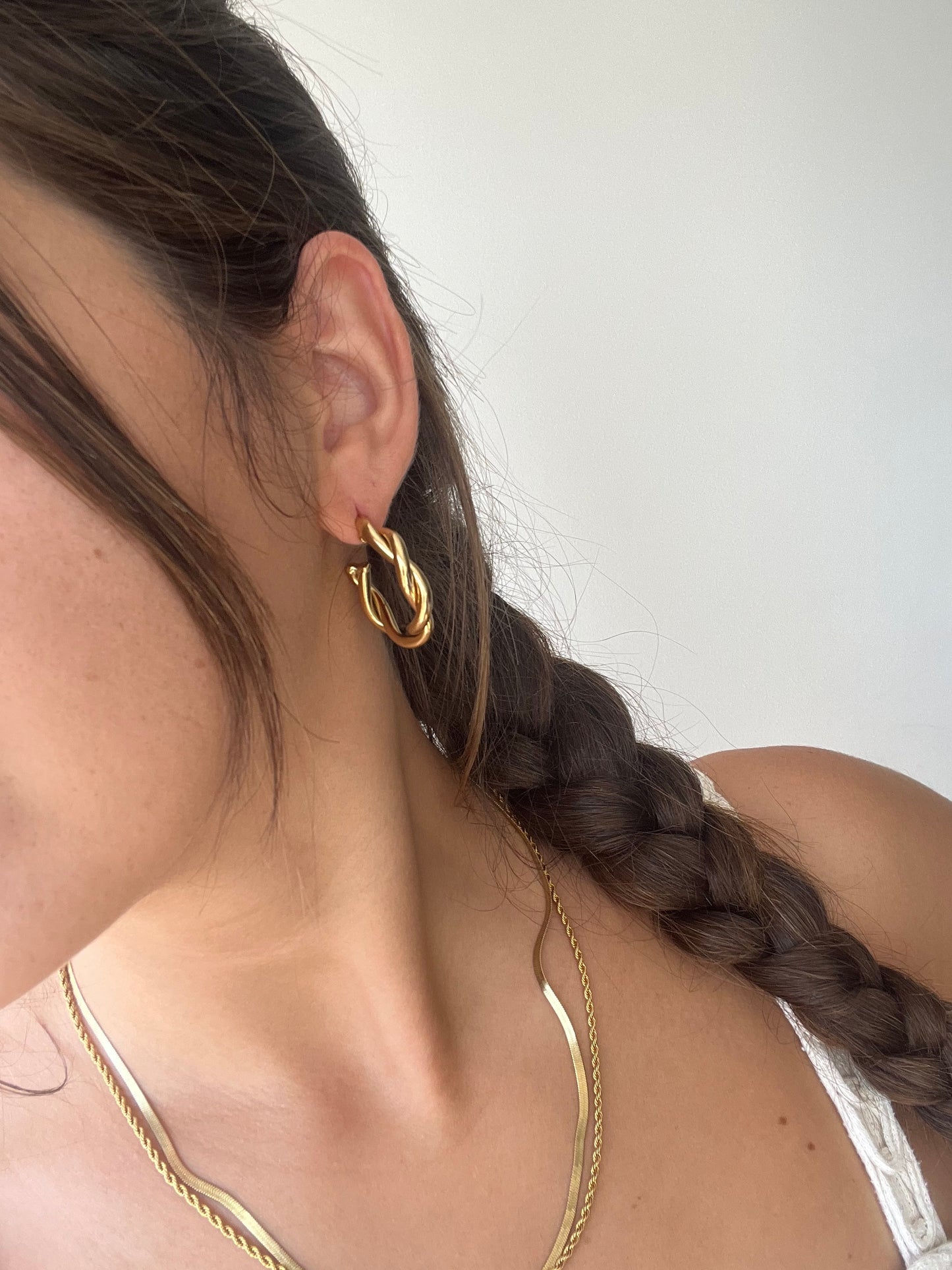 Brincos Cosmos - argolas douradas com design entrelaçado em aço inoxidável.