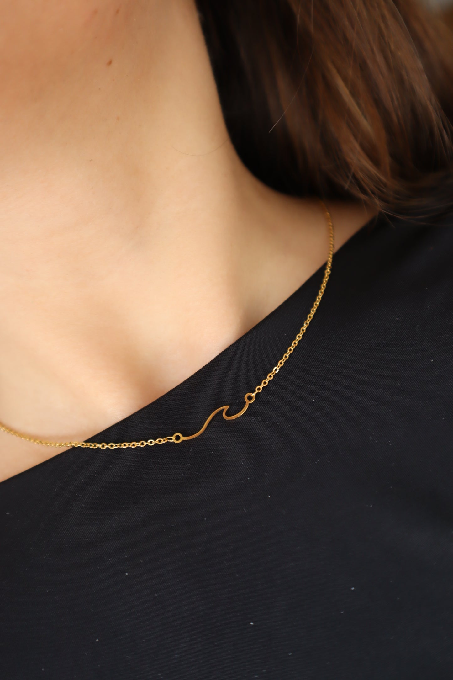 Colar minimalista com pendente de onda em aço inoxidável dourado.