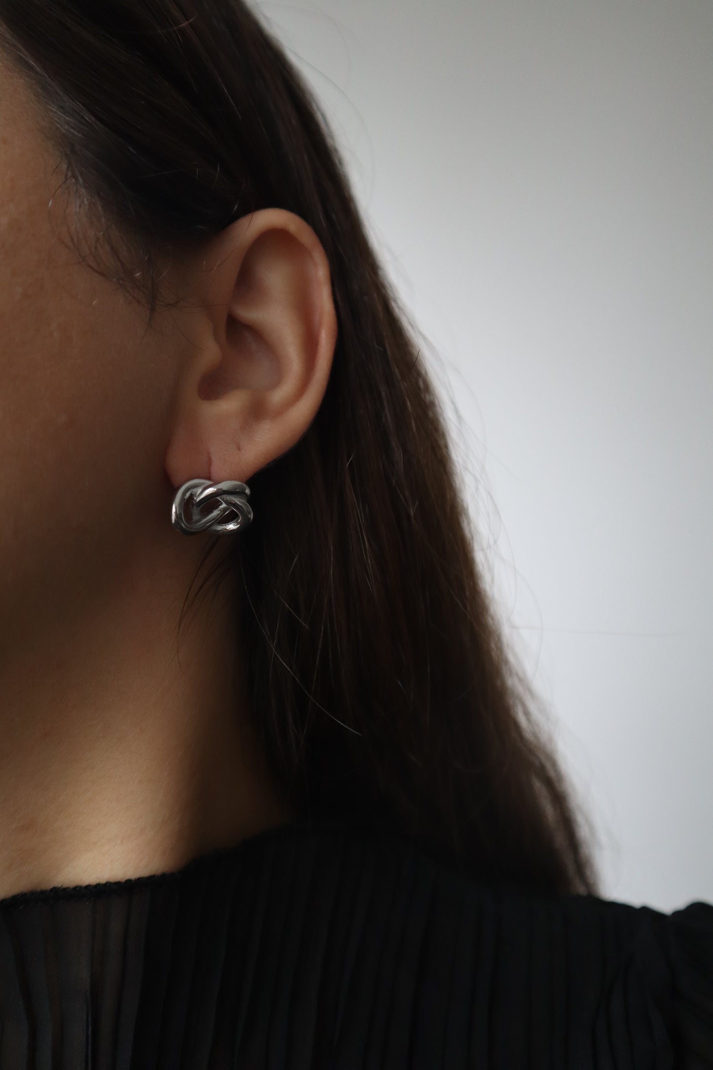 Brincos Hoya em aço inoxidável prateado com design entrelaçado (nó).