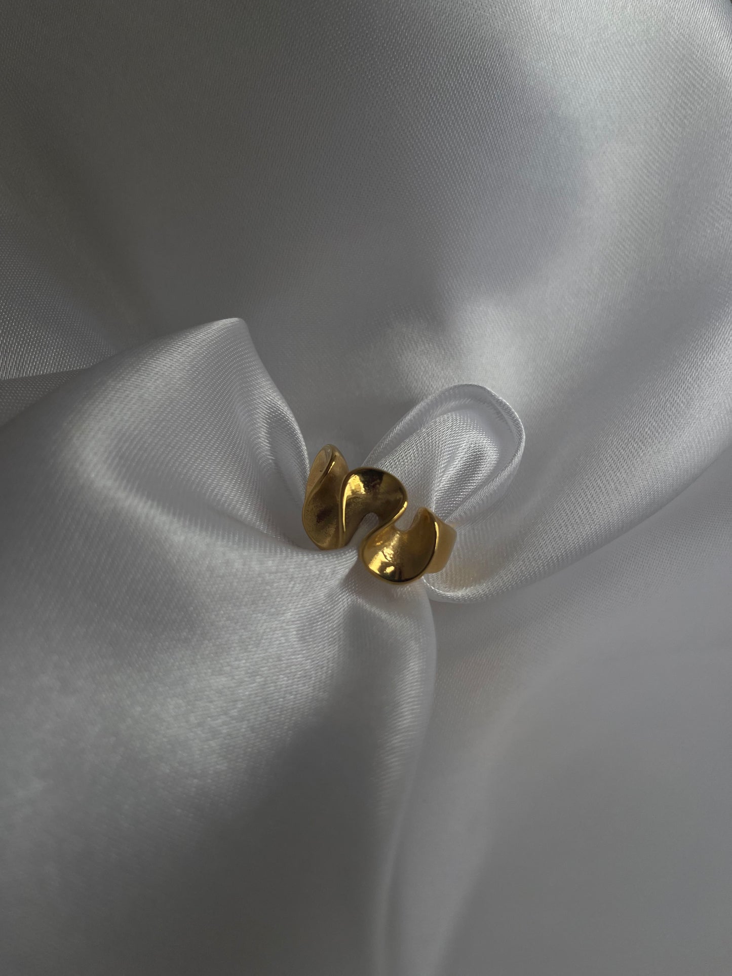 Anel Loureiro em aço inoxidável dourado com design curvo.
