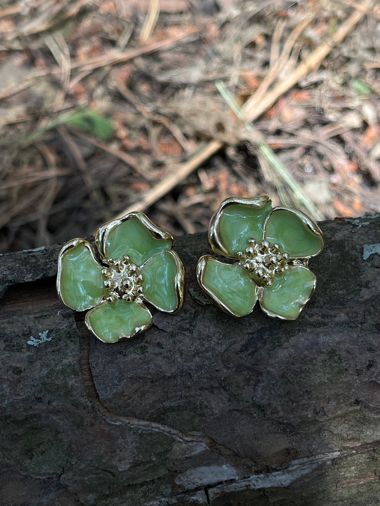 Brincos Magnolia em aço inoxidável dourado com pétalas verdes.