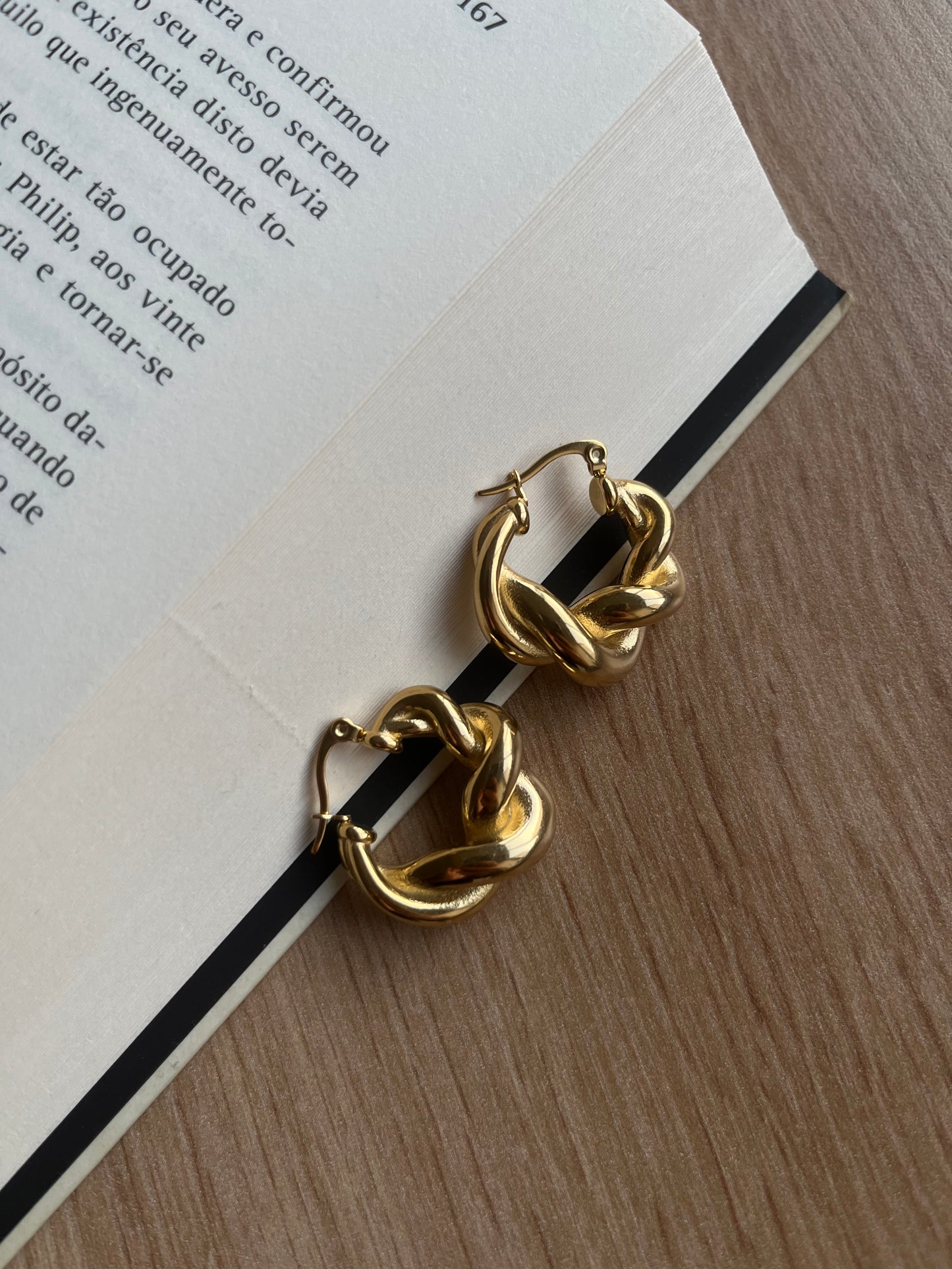 Brincos Malva grossos, em aço inoxidável dourado com design entrelaçado.