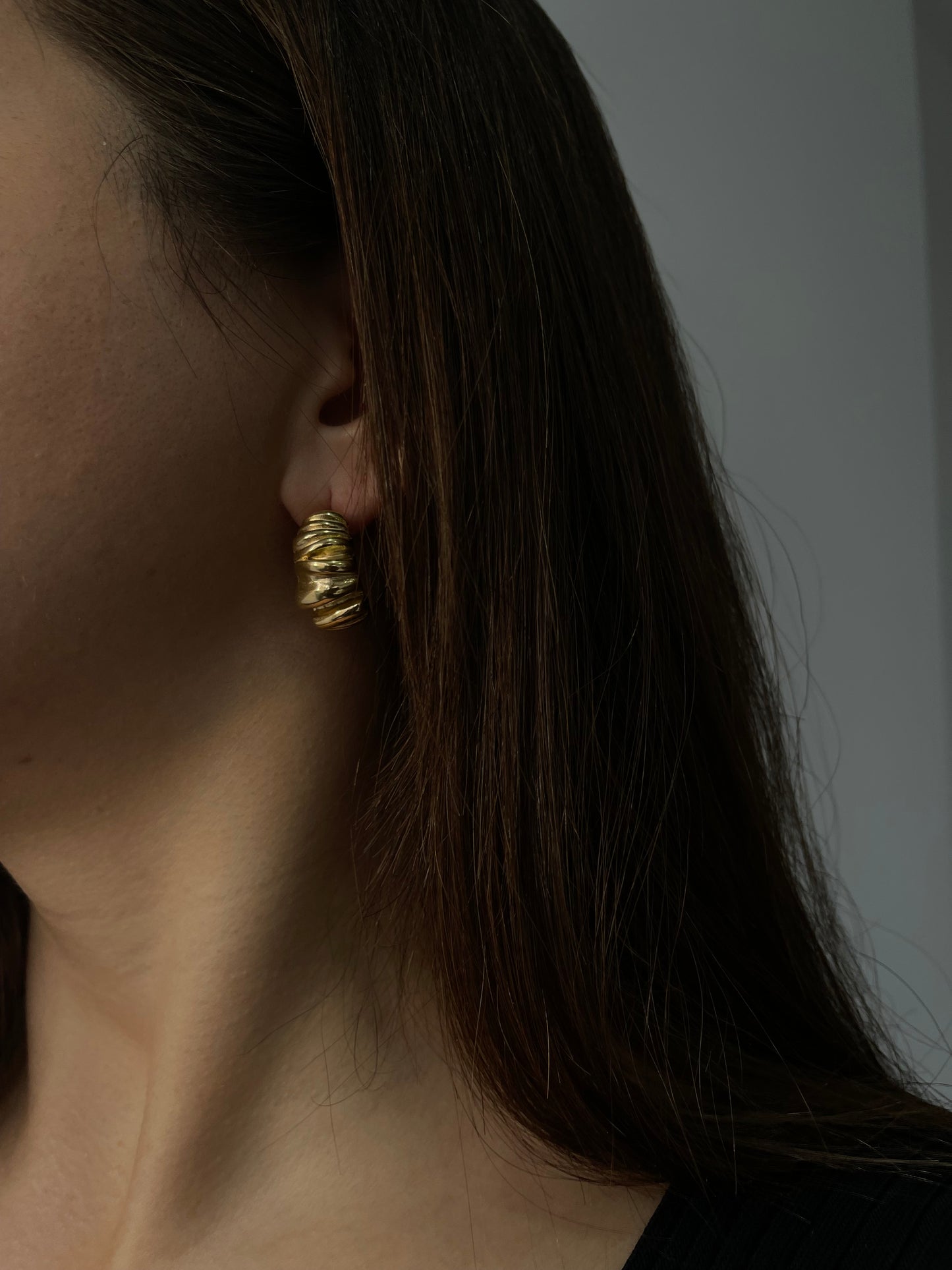 Brincos Melissa em aço inoxidável dourado com design ondulado e robusto.