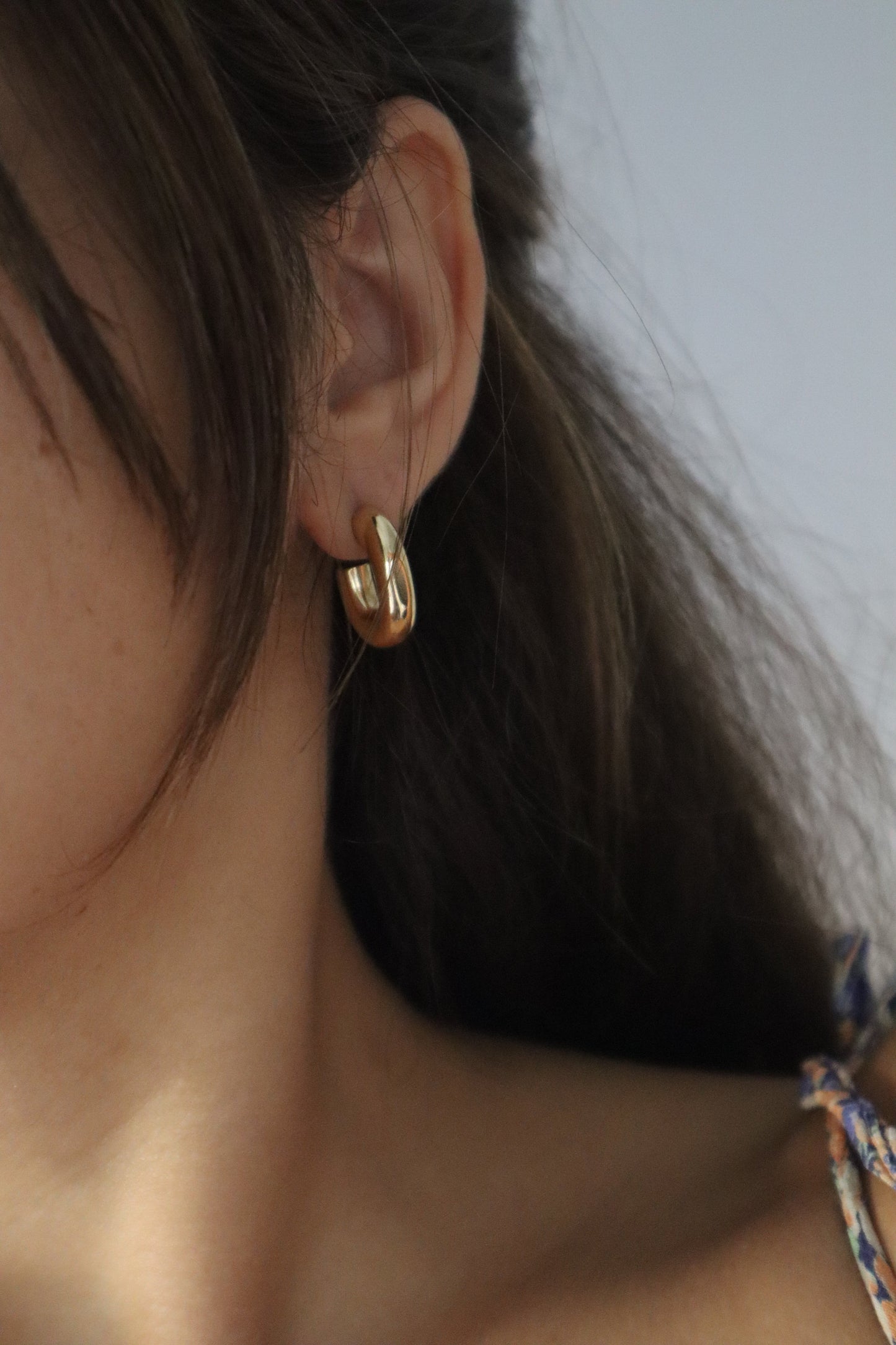 Brincos Camélia em argola dourada oval e grossa em aço inoxidável.