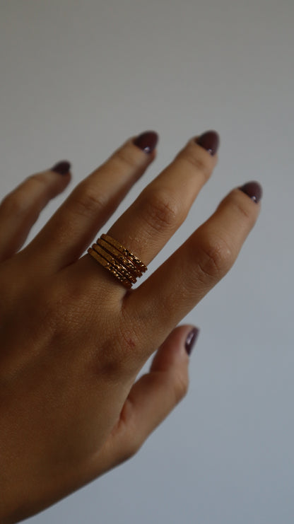 anel Amie dourado com múltiplos aros e textura rugosa em aço inoxidável