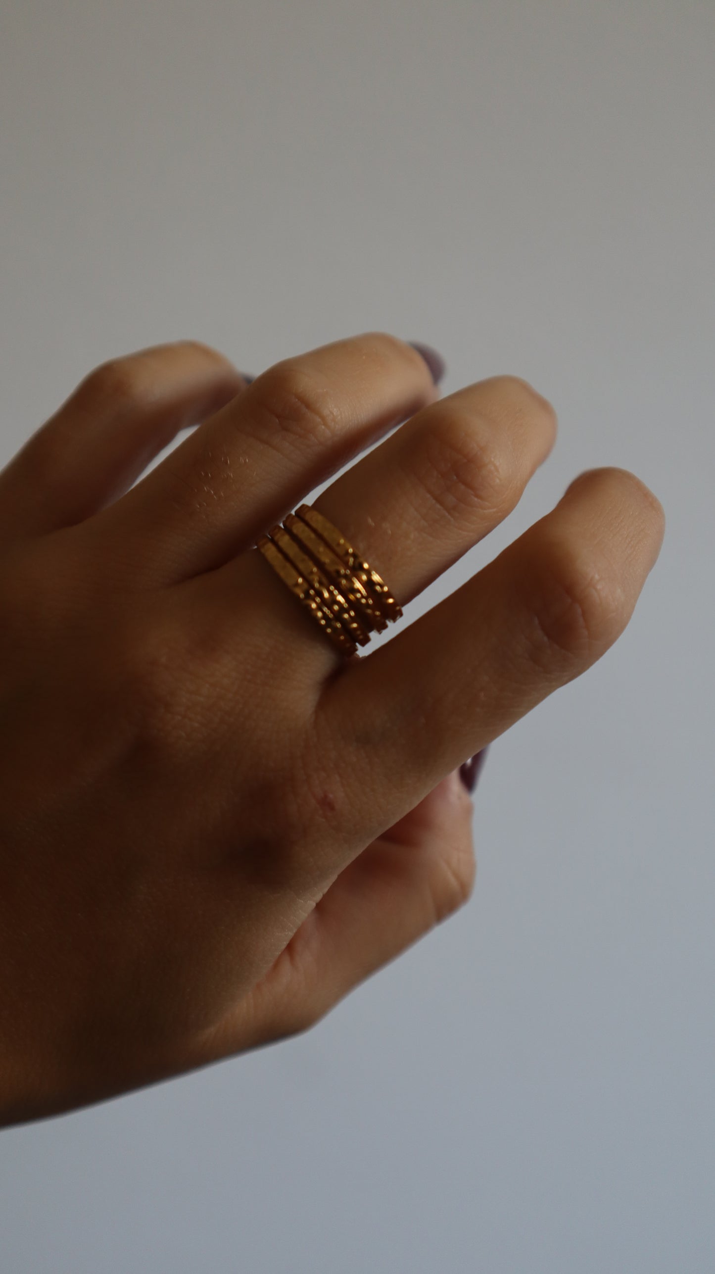 anel Amie dourado com múltiplos aros e textura rugosa em aço inoxidável