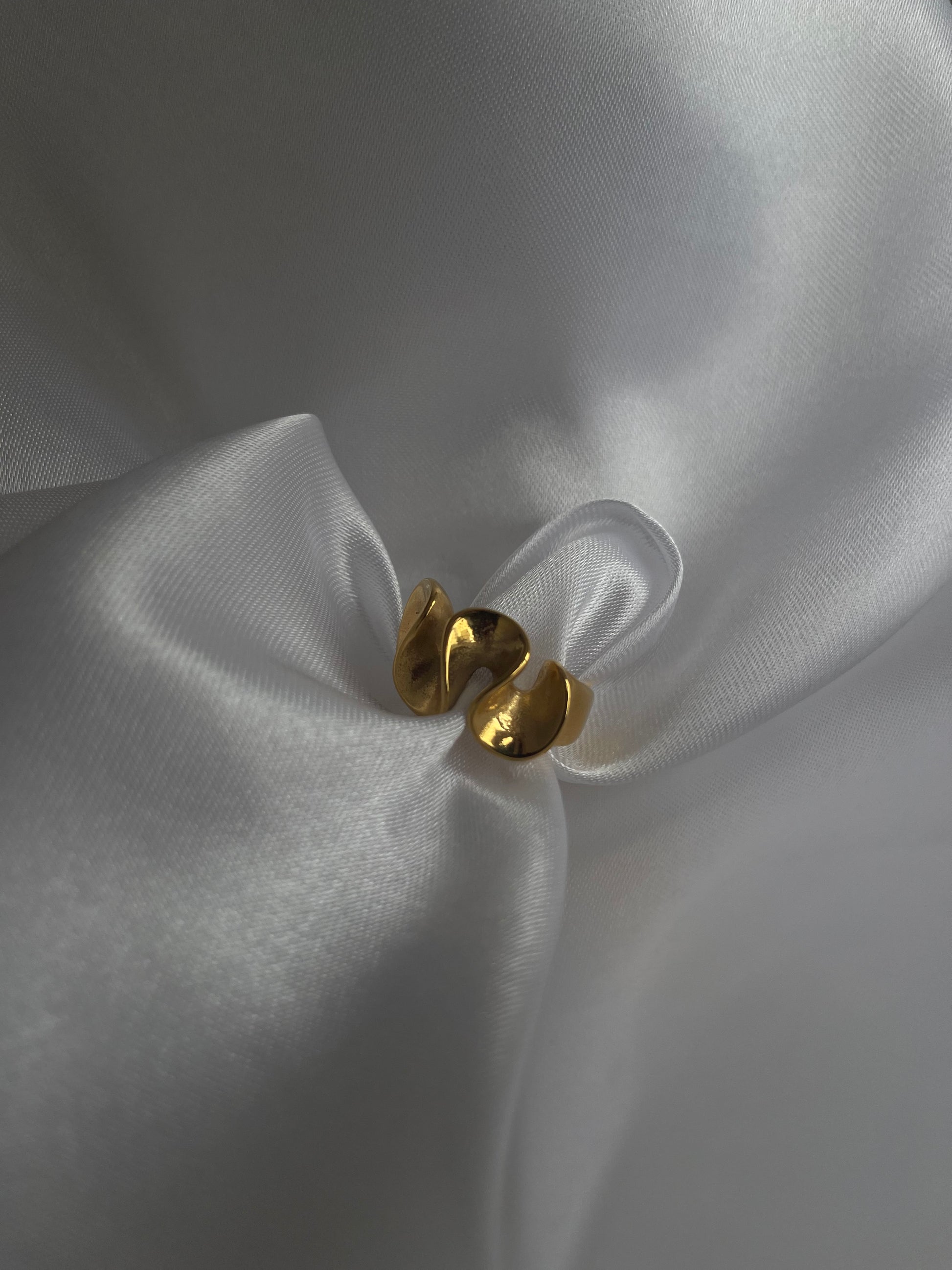 Anel Loureiro em aço inoxidável dourado com design curvo.