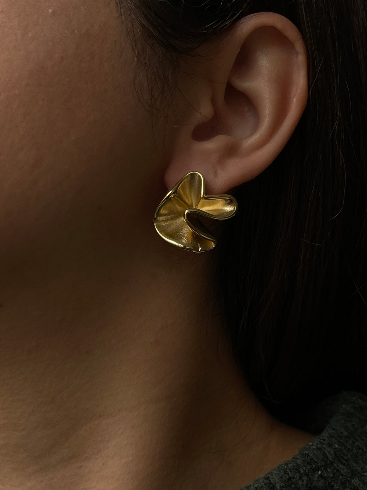 Brincos Loureiro em aço inoxidável dourado com design ondulado e elegante.