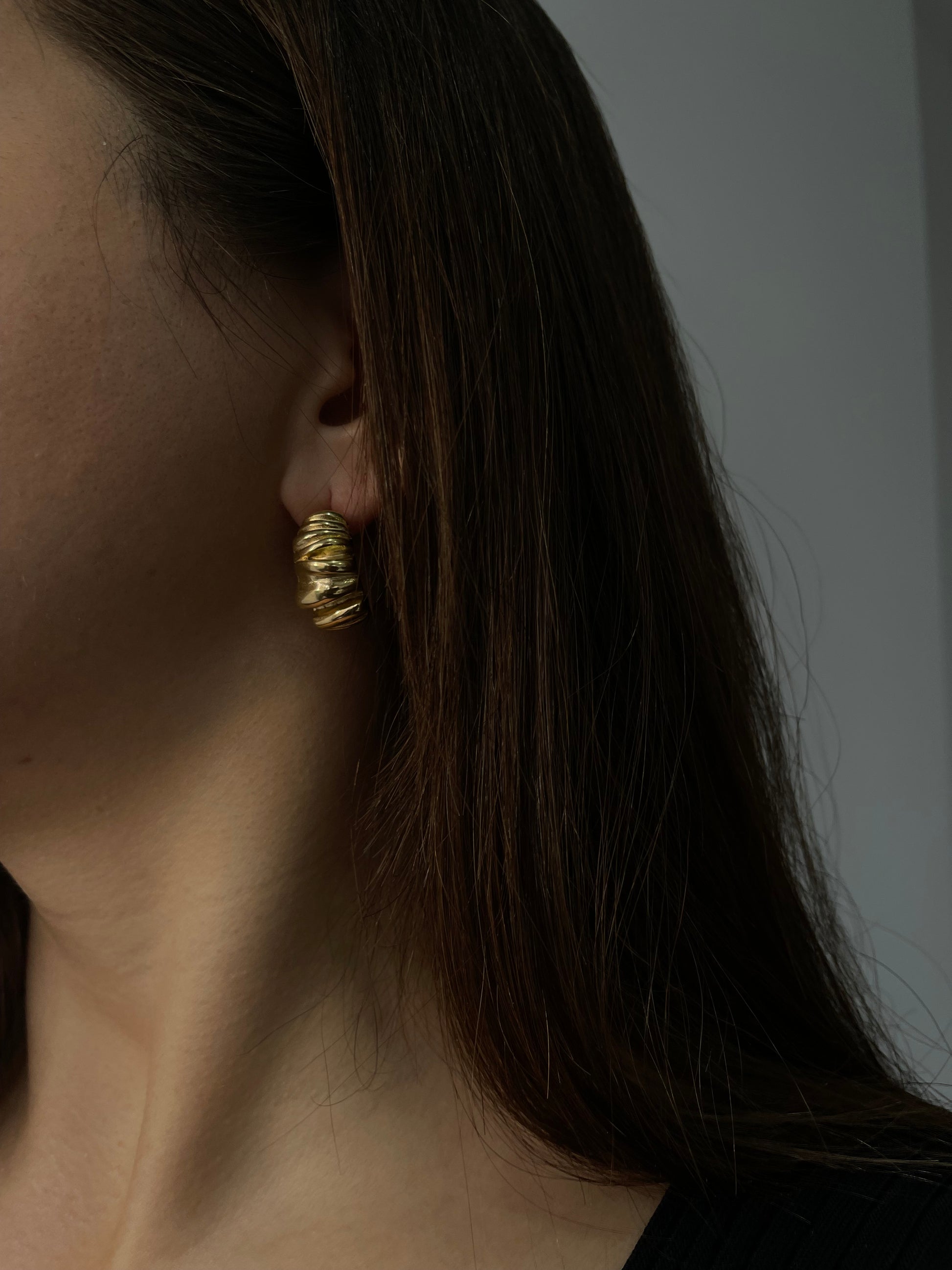 Brincos Melissa em aço inoxidável dourado com design ondulado e robusto.