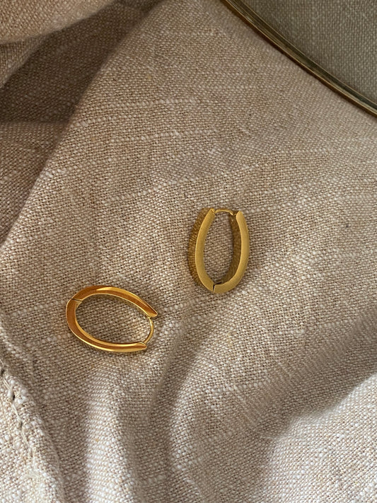 Brincos Olive, argolas de aço inoxidável dourado com design oval minimalista.