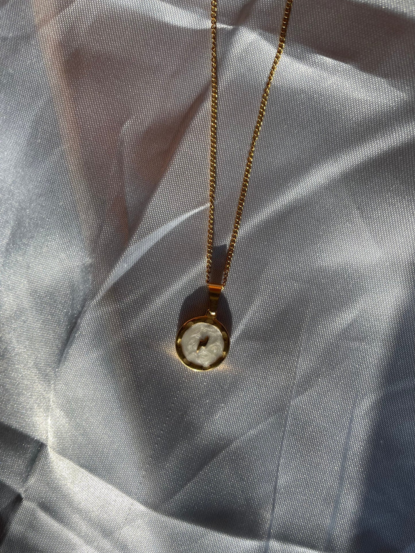 Corrente dourada com pendente redondo com um raio em fundo branco