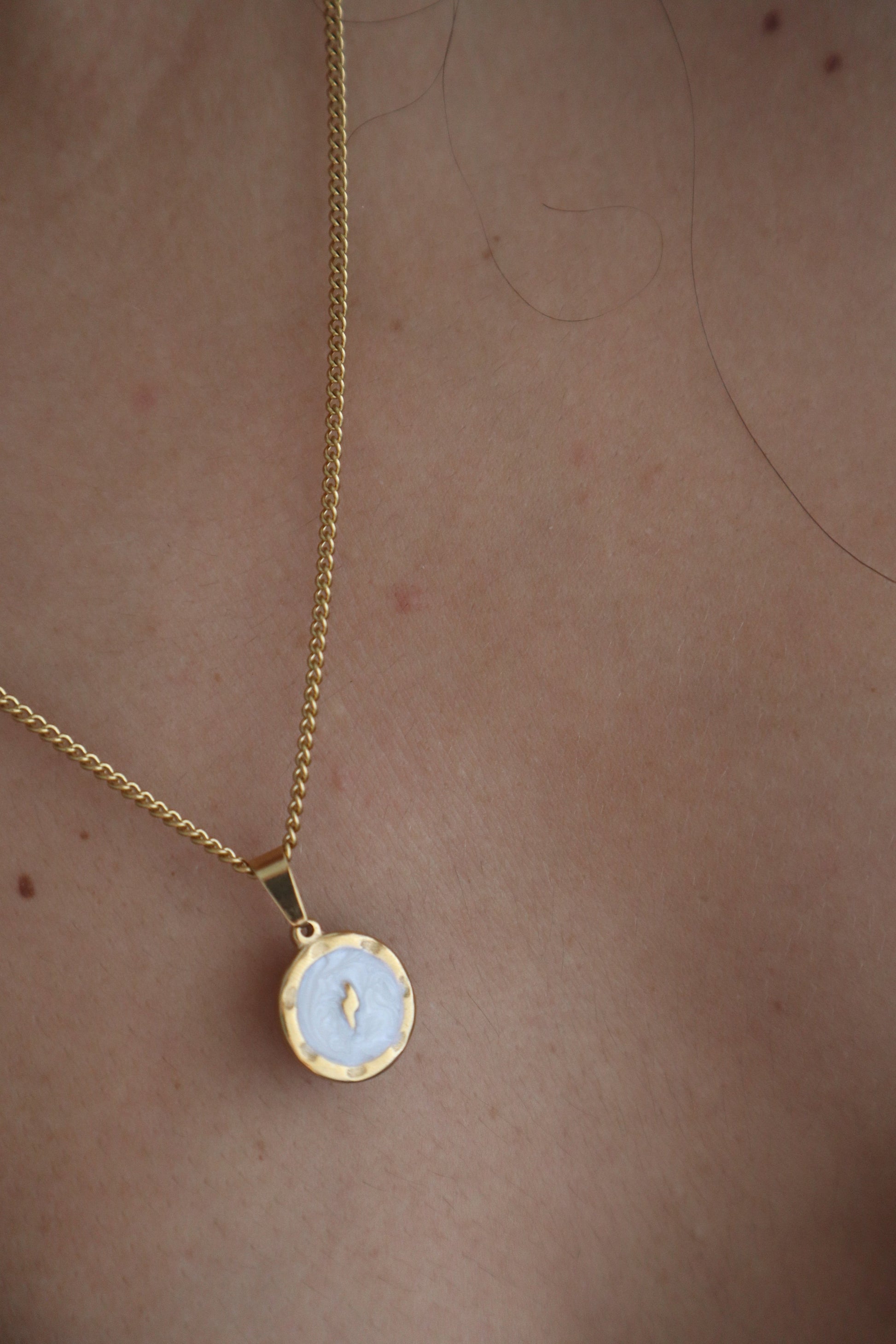 Corrente dourada com pendente redondo com um raio em fundo branco