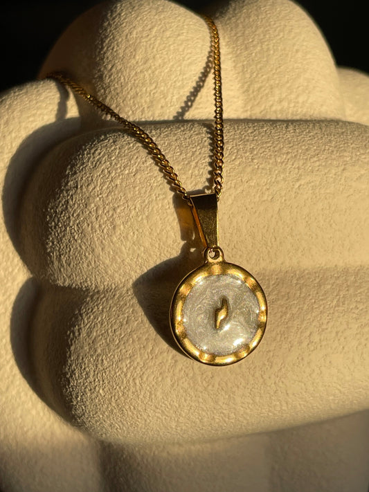 Corrente dourada com pendente redondo com um raio em fundo branco